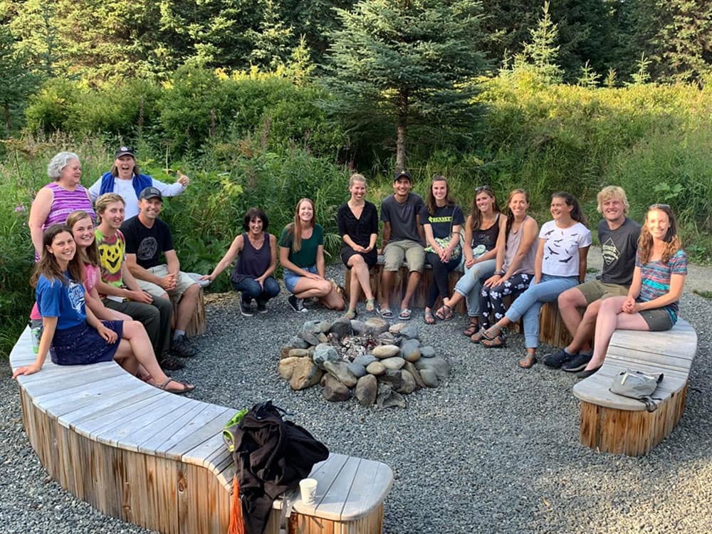 Group of community members sitting around an unlet campfire